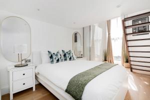um quarto branco com uma cama e um espelho em Majestic Luxury Apartment in Marylebone em Londres