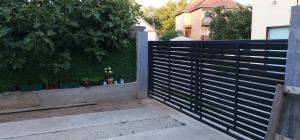 a black fence in front of a hedge with plants at Apartmani Park Vrdnik in Vrdnik