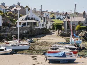 un grupo de barcos sentados en la arena frente a las casas en 11 Bro Celyn, en Holyhead