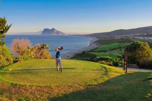 a man playing golf on a hill with a view of the ocean at Estudio Regency Alcaidesa in La Alcaidesa