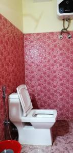 a bathroom with a toilet and a red wall at Hotel Nindik in Gangtok