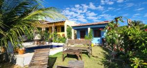 a house with a garden with a bench in the yard at Chalés céu azul in Praia de Quixaba