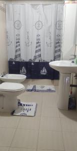 uma casa de banho com um lavatório, um WC e uma cortina de chuveiro. em Piso en la misma playa (Boiro) em Boiro