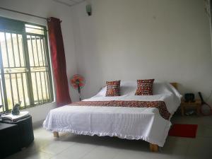 una camera da letto con un letto bianco con cuscini e una finestra di Villa Kikiriki a Kigali