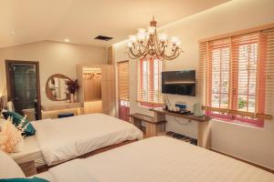 1 dormitorio con 2 camas, TV y ventanas en Villa Hoa Da, en Da Lat
