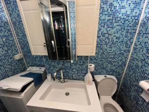a blue tiled bathroom with a sink and a toilet at Apartament central in Târgu Neamț