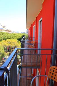 einen Balkon eines Gebäudes mit roten Wänden und Stühlen in der Unterkunft Hotel Neps in Lido di Jesolo