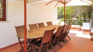 een houten tafel en stoelen met een parasol bij Villa Verde in Procchio