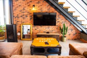 a living room with a television on a brick wall at Loft 90 m2 cosy au calme avec terrasse et parking in Avignon