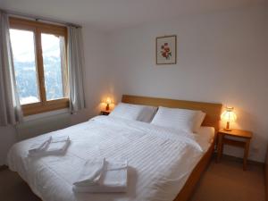 a bedroom with a large white bed with two towels on it at Chalet Eigersunne 2 in Wengen