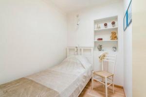 een kleine slaapkamer met een bed en een stoel bij Chez’ Elle in Blankenberge