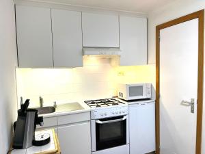 een keuken met witte kasten, een fornuis en een magnetron bij Chez’ Elle in Blankenberge
