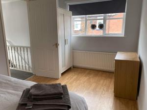 1 dormitorio con cama, ventana y suelo de madera en Cozy 2-bedroom property with shared garden, en Sunderland
