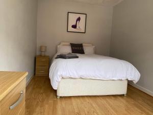 1 dormitorio con cama blanca y tocador con mesita de noche en Cozy 2-bedroom property with shared garden, en Sunderland