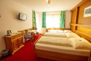 a hotel room with two beds and a desk and a sink at Haus Josef in Mayrhofen