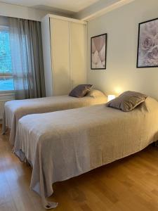 two beds in a room with a window at Tasokas jokiranta-asunto lähellä ydinkeskustaa in Turku
