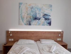 two beds in a bedroom with a painting on the wall at Neon Hotel in Stalís
