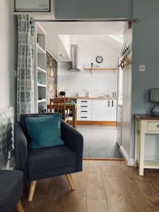 a living room with a chair and a kitchen at Stiwdio Eithinog in Caernarfon