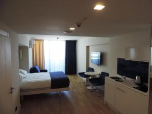 a hotel room with a bed and a flat screen tv at Black Sea Twin tower in Batumi