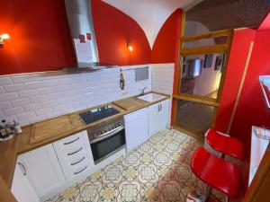 a small kitchen with red walls and white cabinets at GALLEGOS16 in Cáceres