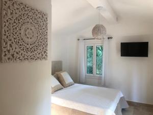 biała sypialnia z łóżkiem i oknem w obiekcie Les Mazets de la Cascade w mieście Salernes