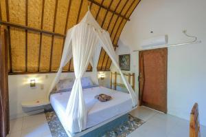 a bedroom with a bed with a mosquito net at 3 Angels Homestay in Gili Islands