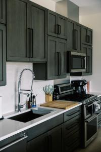a kitchen with black cabinets and a sink at THE NEST: Luxury, History, Balcony, Memories in Traverse City