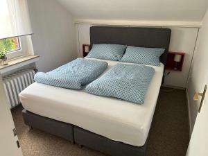 een bed met blauwe kussens in een kamer bij Ferienwohnung "An der alten Mühle" 2 Schlafzimmer, Südbalkon, Gartenterrasse & Wallbox, 100 qm in Bad Bentheim