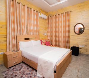 a bedroom with a bed and a mirror and curtains at Bays Boutique Apartment in Accra