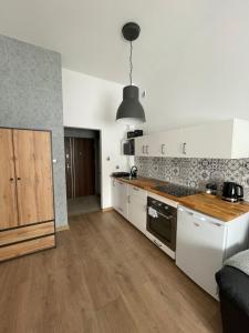 a kitchen with white cabinets and a wooden counter top at Mini apartament Ostróda in Ostróda