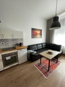 een woonkamer met een zwarte bank en een tafel bij Mini apartament Ostróda in Ostróda