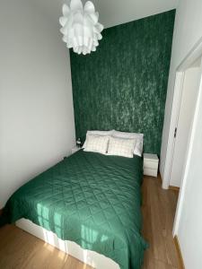 a bedroom with a green bed and a chandelier at Mini apartament Ostróda in Ostróda