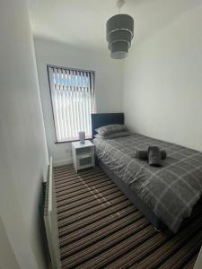Schlafzimmer mit einem Bett und einem Fenster in der Unterkunft Modern 3 bedroom house close to the city centre in Belfast