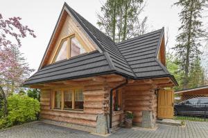 uma pequena cabana de madeira com um telhado preto em Apartament pod Skocznią em Zakopane