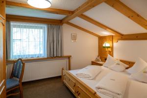 a bedroom with a bed and a chair and a window at Landhaus Marion in Holzgau