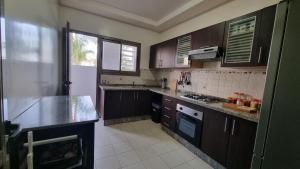 a kitchen with wooden cabinets and a counter top at My Cosy Place Rabat - Skhirat 2min de la plage avec Piscine in Skhirat