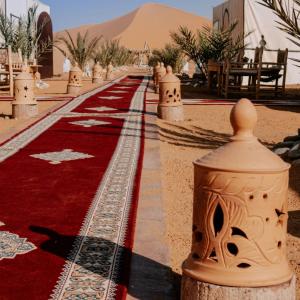 a red carpet in the desert with a mountain in the background at Deep Desert Camp in Merzouga