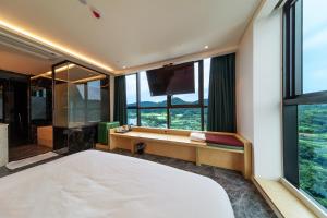 釜山にあるThe Club Hotel Gijang Yeonhwariの大きなベッドと大きな窓のある寝室