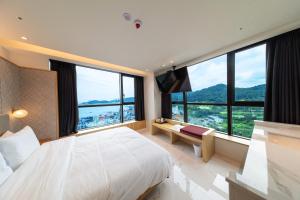 1 dormitorio con 1 cama grande y ventanas grandes en The Club Hotel Gijang Yeonhwari en Busan