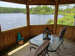 a screened in porch with a glass table and chairs at Fiddler's Lake Escape in Gabarus