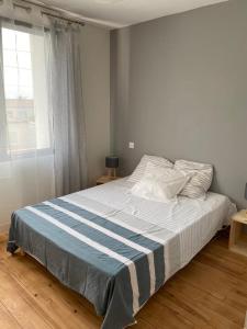 um quarto com uma cama com um cobertor azul e branco em Villa au calme dans un écrin de verdure em Aytré