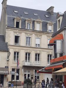 een groot gebouw met een zwart dak op een straat bij Studio Neptune in Arromanches-les-Bains