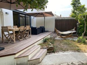 une terrasse en bois avec un hamac et un parasol dans l'établissement Villa au calme dans un écrin de verdure, à Aytré