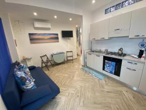 ein Wohnzimmer mit einem blauen Sofa und einer Küche in der Unterkunft MarEtna in Giardini-Naxos