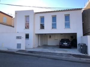 um edifício branco com um carro estacionado numa garagem em Appartement T3 dans maison neuve 7 couchages em La Seyne-sur-Mer
