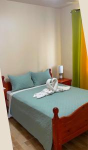 The Golden Inn في Marigot: يوجد بجعتين فوق سرير