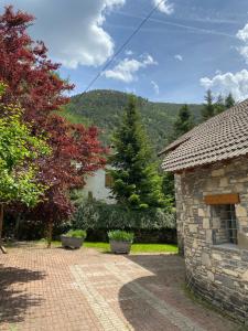 a stone building with trees and a mountain in the background at Casa Marian Villanua in Villanúa