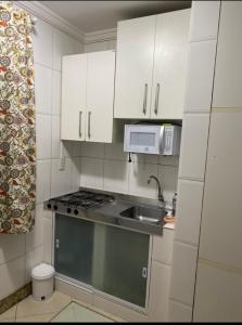 a small kitchen with a sink and a microwave at Casa Sol e Mar Beira-mar in Ilhéus