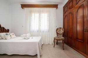 a bedroom with a bed and a chair and a window at Villa Roses - Alcúdia in Alcudia