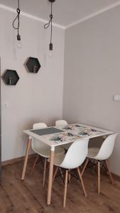 una mesa de comedor con sillas blancas alrededor en Apartament Tuwima Park en Ełk